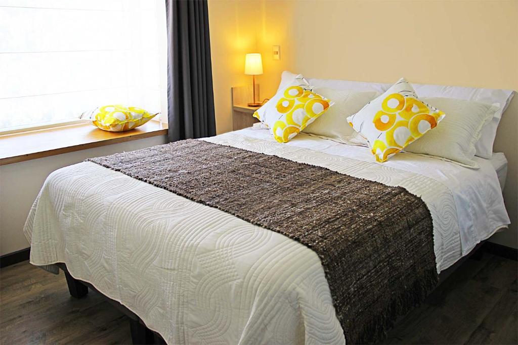 a bedroom with a large bed with yellow and white pillows at Departamentos Nómades del Lago in Puerto Varas