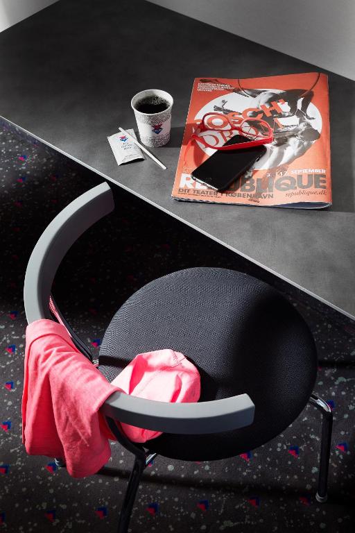 a desk with a chair with a book and a magazine at Cabinn Copenhagen in Copenhagen