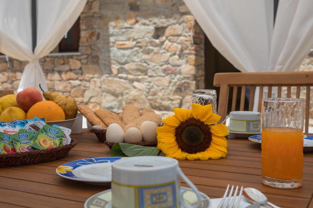 uma mesa de madeira com um pequeno-almoço de ovos e frutas em Arroccas de is Istellas em Arbus