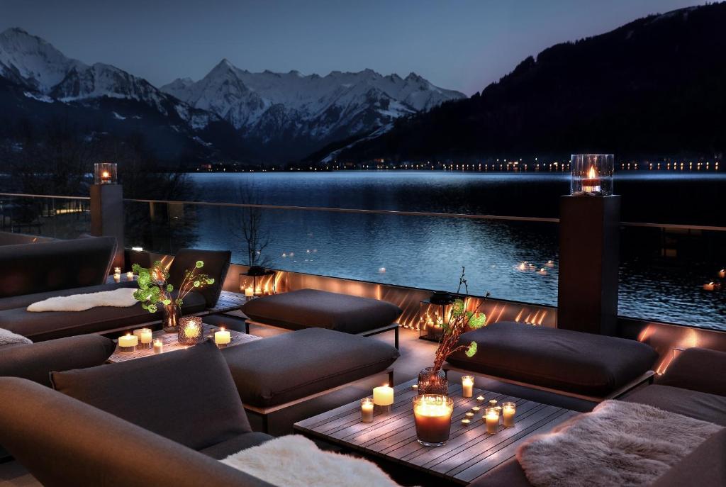 a patio with couches and a lake at night at Seehotel Bellevue in Zell am See
