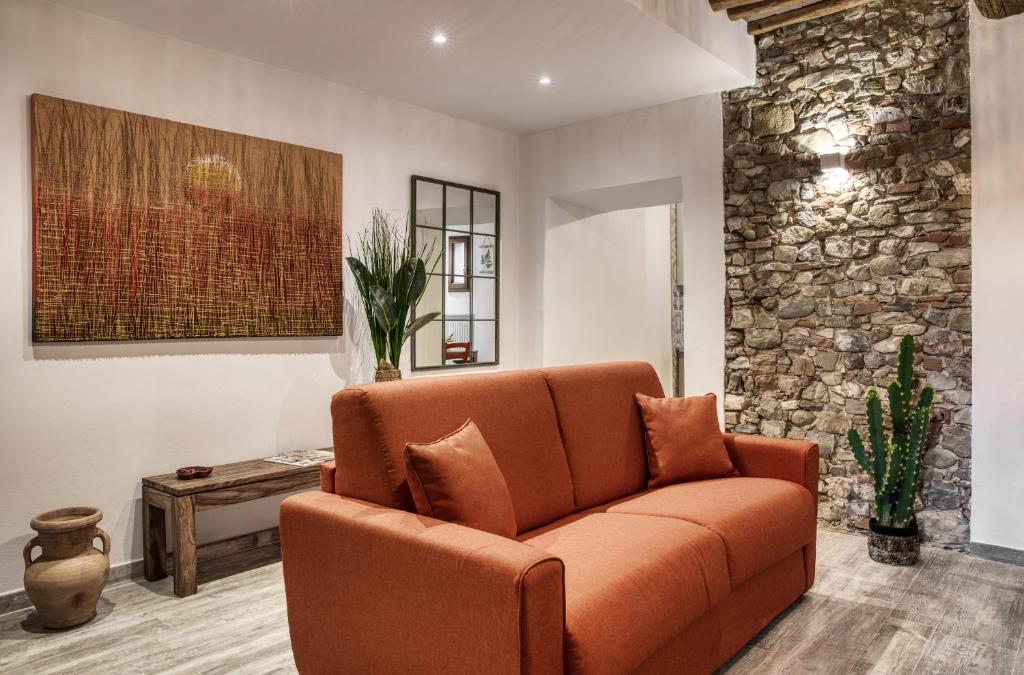 un sofá naranja en una sala de estar con una pared de piedra en Il Nido nel Chianti en Greve in Chianti