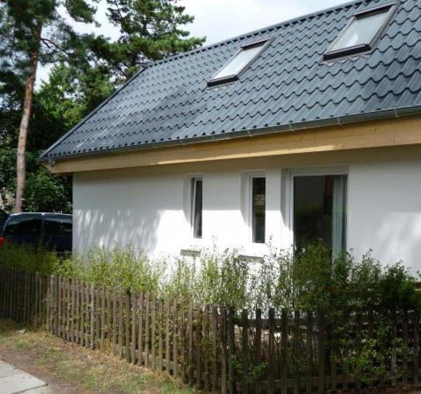 une maison blanche avec un toit noir et une clôture dans l'établissement Ferienhaus Fredy, à Zinnowitz