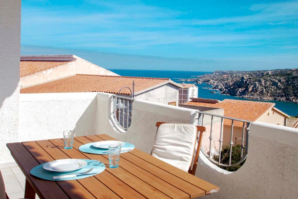 una mesa de madera en un balcón con vistas al océano en Quadrilocale Laura, en Santa Teresa Gallura