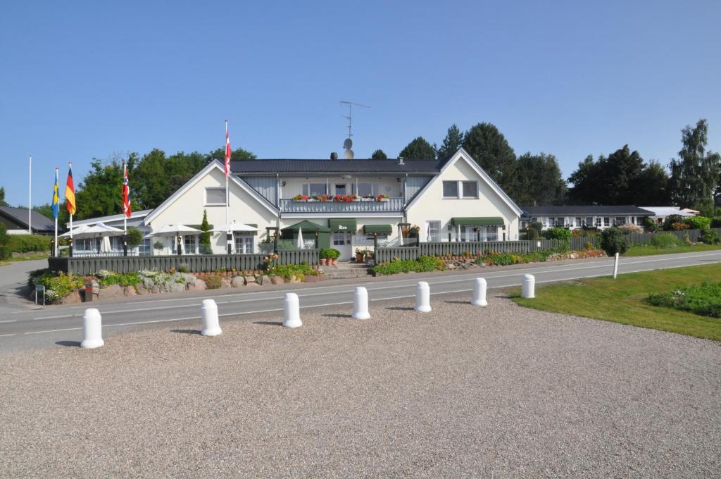 un edificio con postes blancos al lado de una carretera en Hotel Fjordkroen en Tappernøje