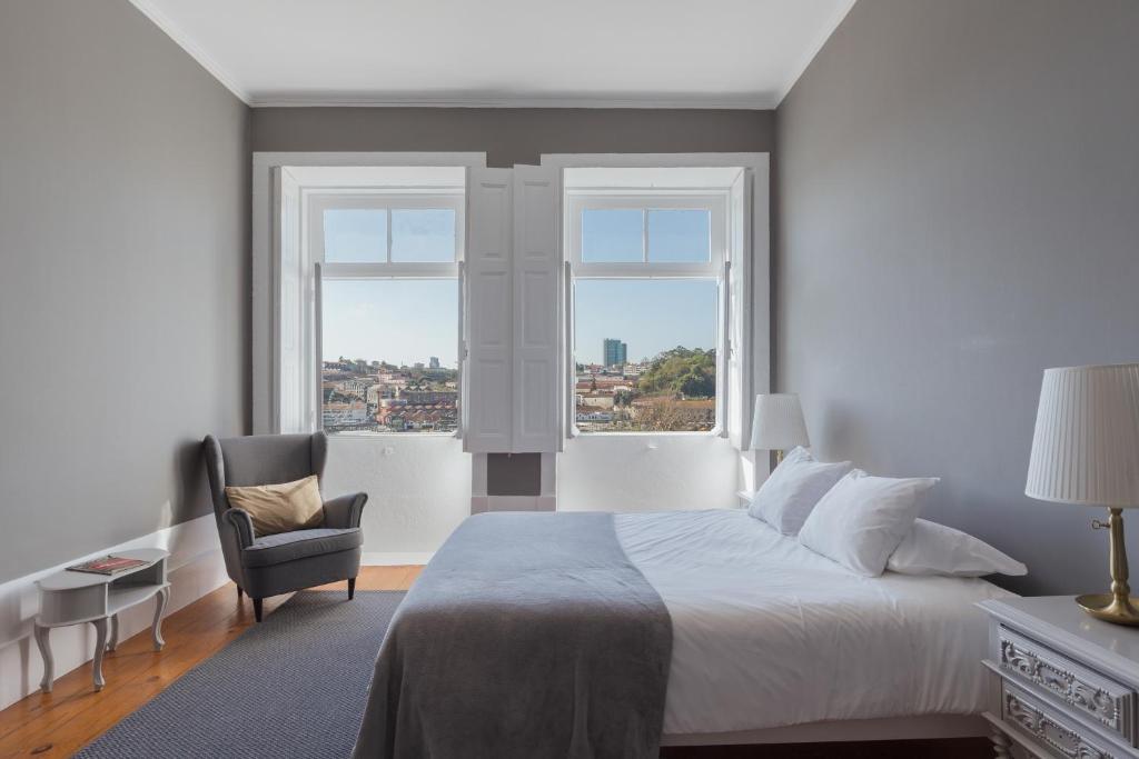 a bedroom with a bed, chair and a window at GuestReady - INNVICT in Porto