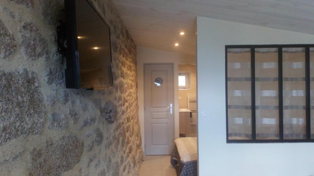 um quarto com uma parede de pedra e uma porta com um espelho em Le Petit Logis em Puy-du-Fou