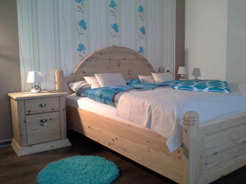 a bedroom with a wooden bed with a night stand and a blue rug at Gasthaus Hinterländer Schweiz in Gladenbach