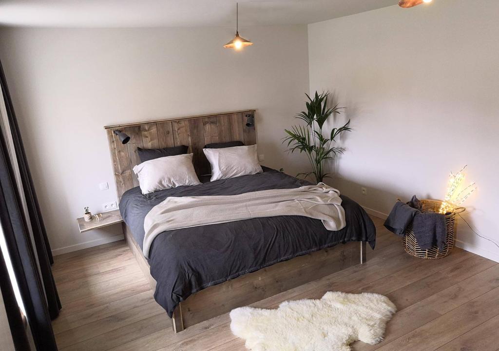 Schlafzimmer mit einem großen Bett mit einem Kopfteil aus Holz in der Unterkunft Bed en Bezem in Laarne