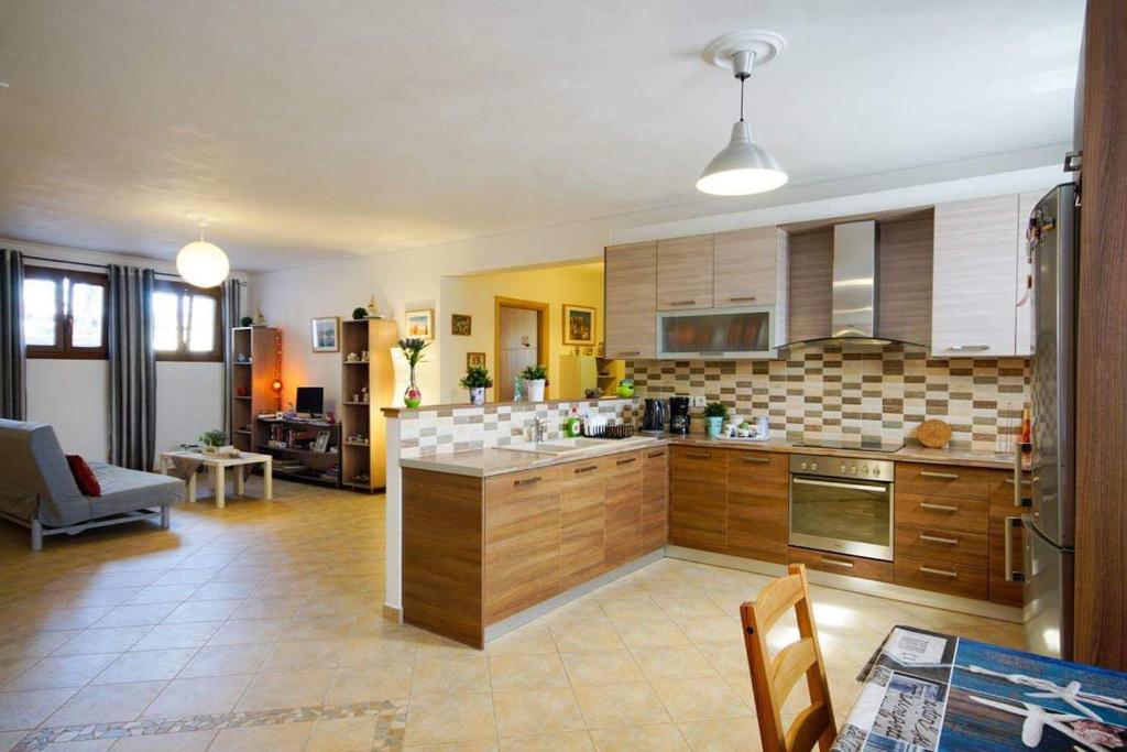 a kitchen with wooden cabinets and a living room at Anemona Apartment in Mithymna