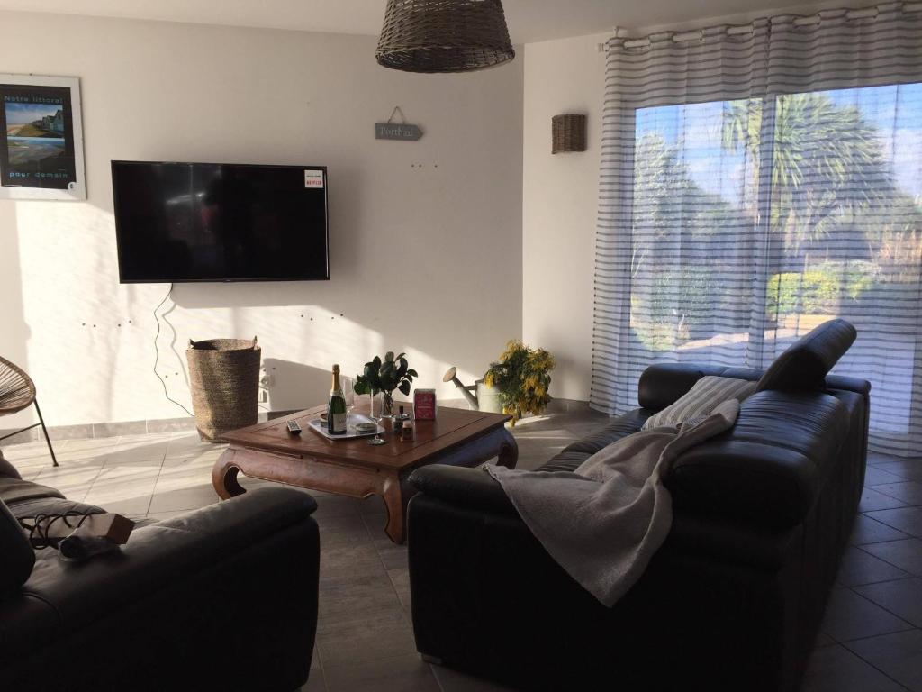 a living room with two couches and a tv at VILLA THEDIEBERT in Barneville-Carteret