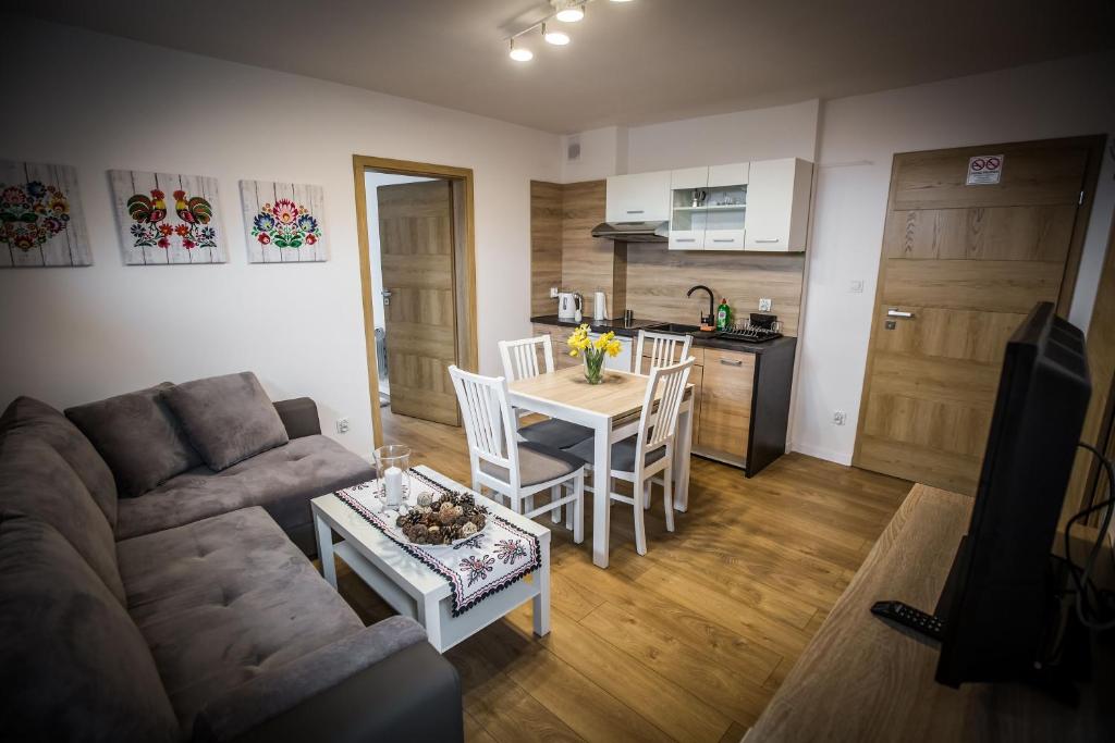 sala de estar con sofá, mesa y cocina en Apartamenty przy skoczni, en Szczyrk