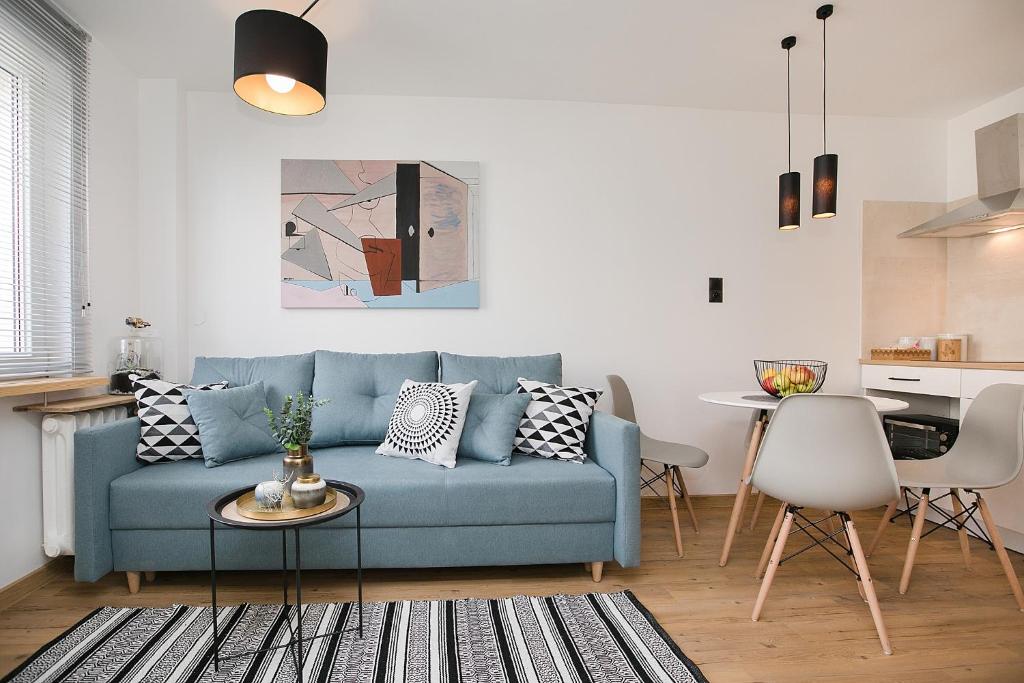 a living room with a blue couch and a table at Studio 49 Apartment in Ełk