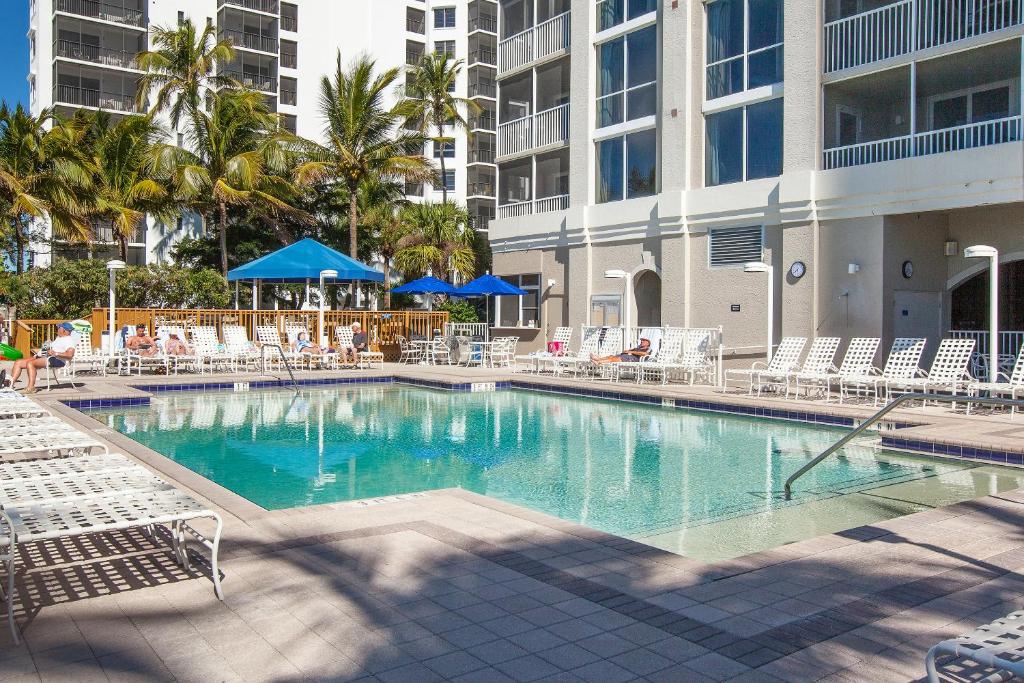 una gran piscina con sillas y sombrillas azules en GullWing Beach Resort, en Fort Myers Beach