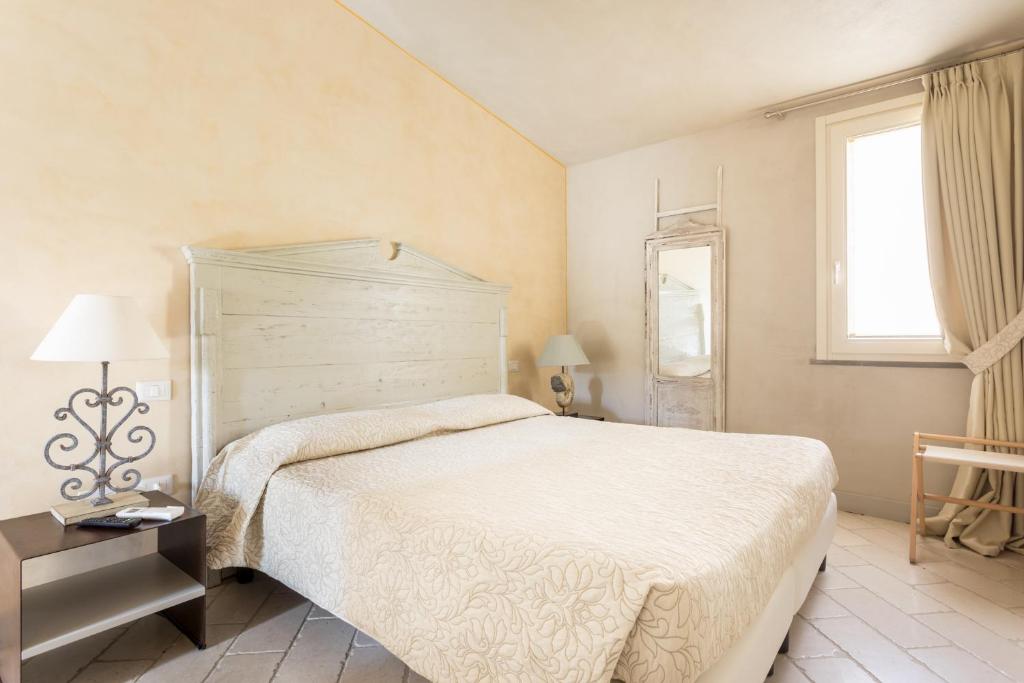 a bedroom with a large white bed and a window at Il Cortiletto Hotel Maison in Tresnuraghes