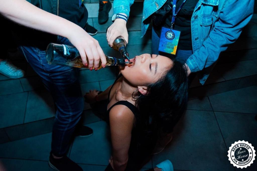 a woman is sitting down drinking from a bottle at Greg&Tom Beer House Hostel in Krakow