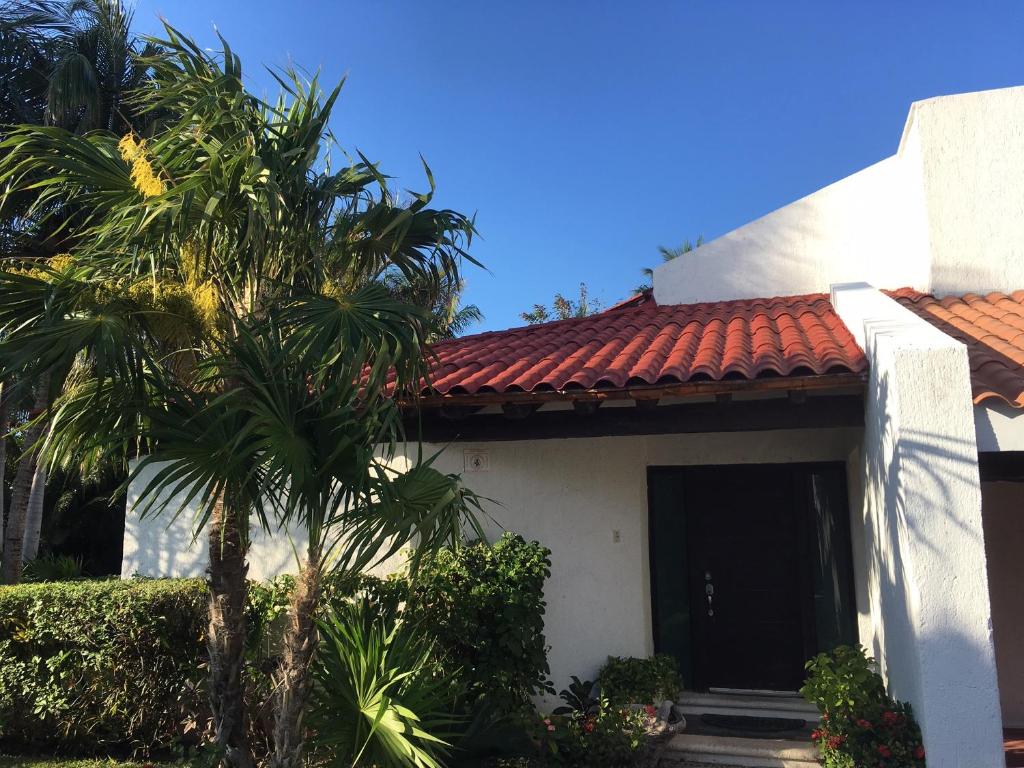 a white house with a red roof and a palm tree at Large House - walking to beach - 10 guests! in Cancún