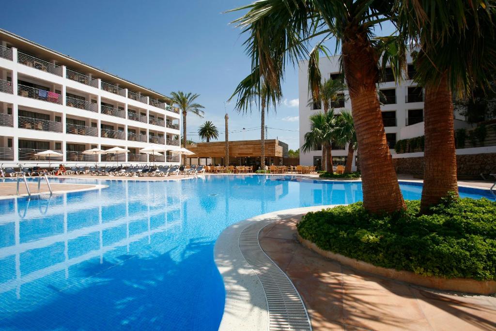 a swimming pool with a palm tree and a hotel at Hotel Alcossebre in Alcossebre