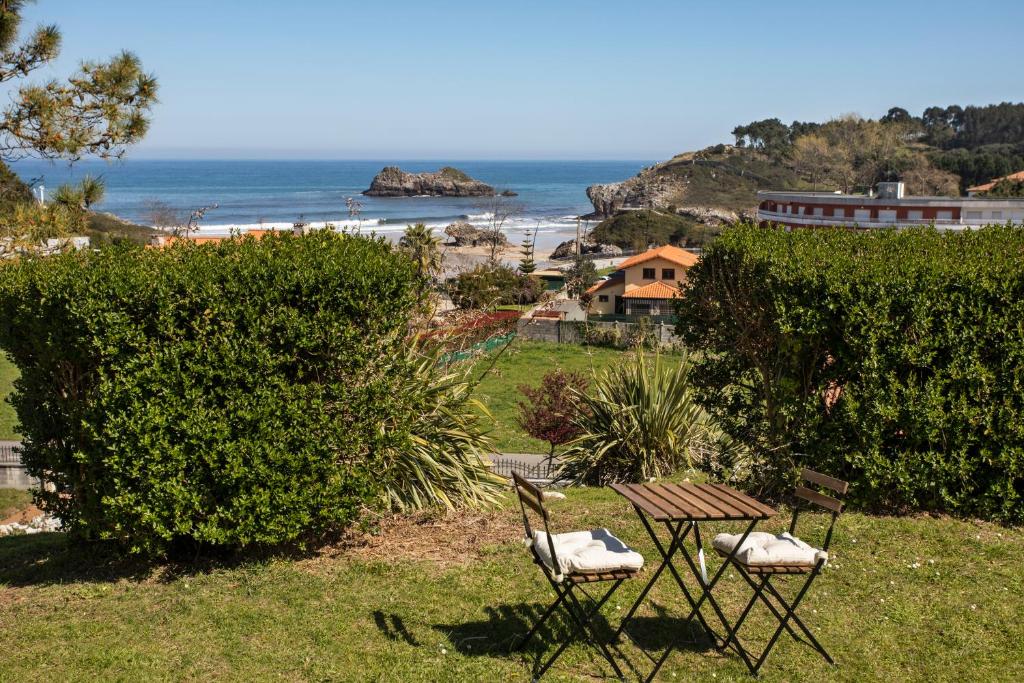 a picnic table and two chairs sitting in the grass near the ocean at Apartamento El Sauce de Amalia in Celorio