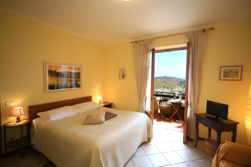 a bedroom with a bed and a television and a balcony at Casa Milena in San Gimignano