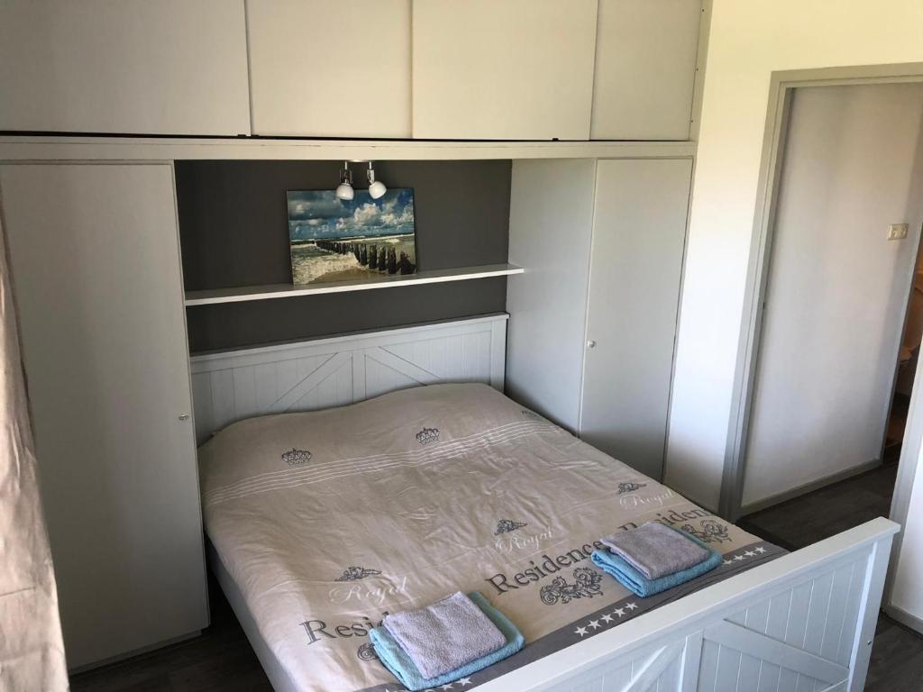 een klein bed in een kamer met witte kasten bij Appartement Dishoek in Koudekerke