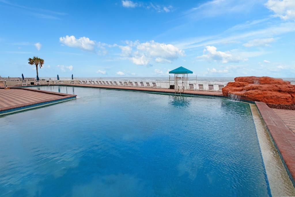 a swimming pool next to a beach with the ocean at Westgate Harbour Beach Resort in Daytona Beach