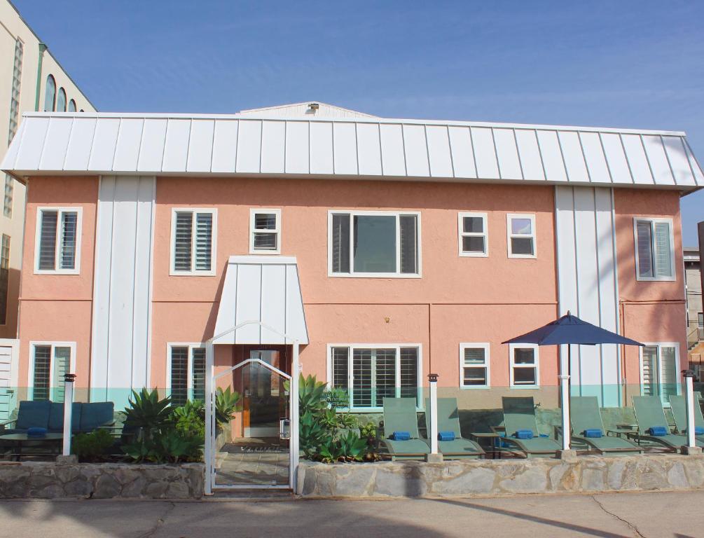a pink and white building with chairs and an umbrella at Venice on the Beach Hotel in Los Angeles