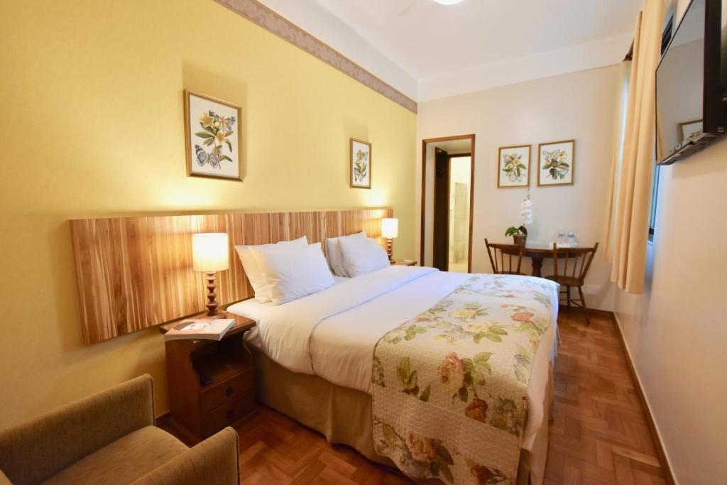 um quarto de hotel com uma cama e uma cadeira em Hotel York em Petrópolis