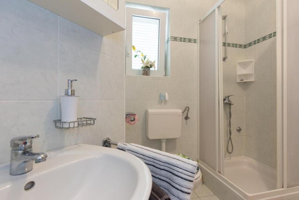a white bathroom with a sink and a shower at Apartments in Vrbnik/Insel Krk 36771 in Vrbnik