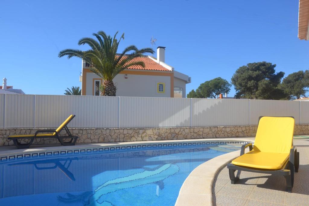 una piscina con 2 sillas amarillas junto a una valla en Villa Barros by GalanteVasques, en Carvoeiro