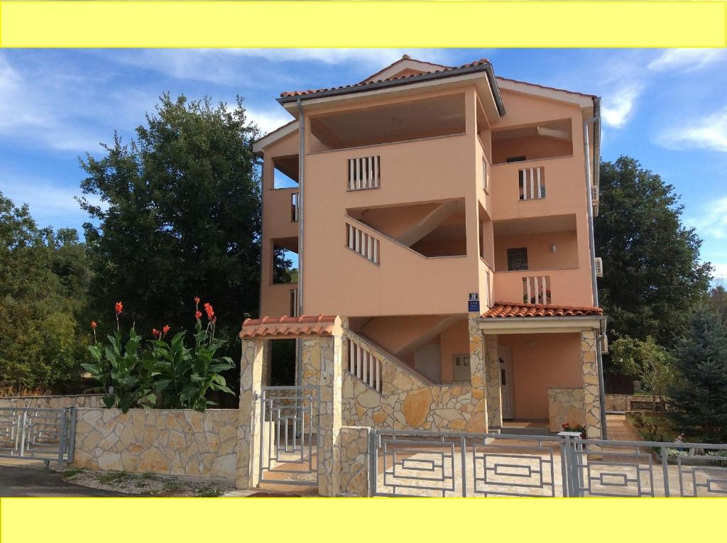 a tall building with a fence in front of it at Apartments Coral, Klimno, island Krk in Klimno