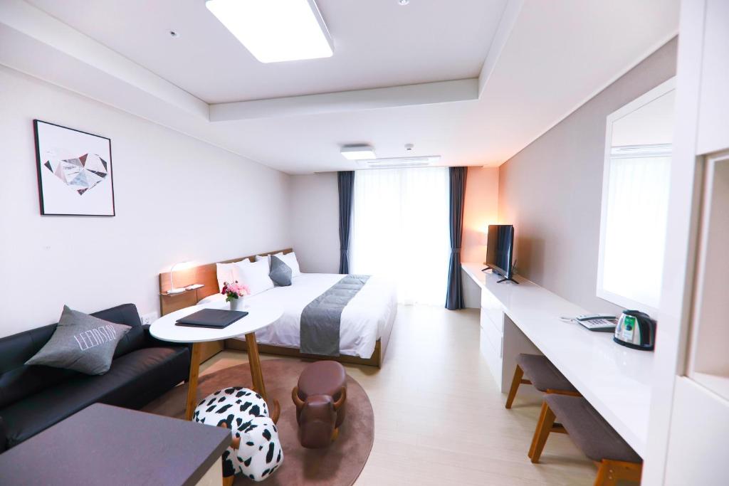 um quarto de hotel com uma cama e um sofá em Geoje Leein Stay Hotel em Geoje