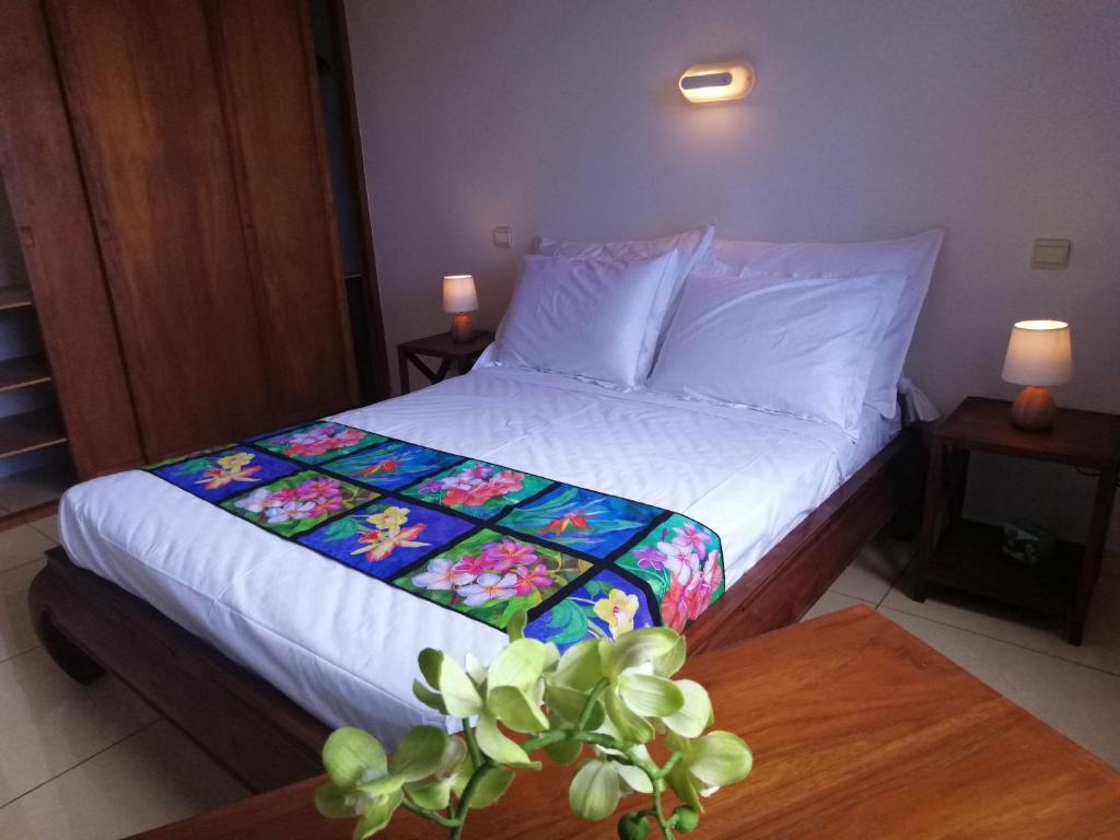 1 dormitorio con cama y mesa con edredón de flores en Tahiti - Le Condo Ariitea, en Pirae