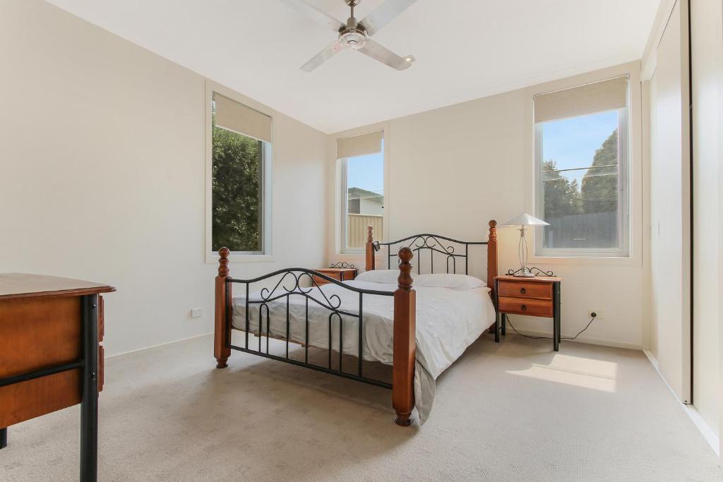 a bedroom with a bed and a table and windows at Nautilus in Lakes Entrance