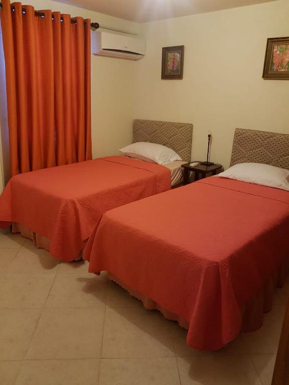 two beds in a room with red curtains at Breezy Apts in Saint Philip
