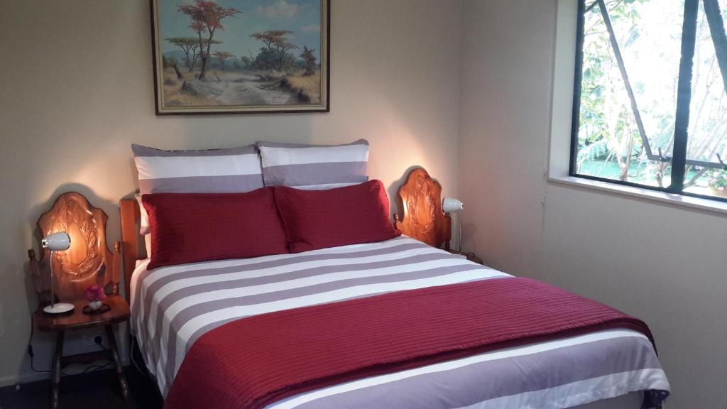 a bedroom with a large bed with red and white pillows at Jade Bed & Breakfast in Blenheim