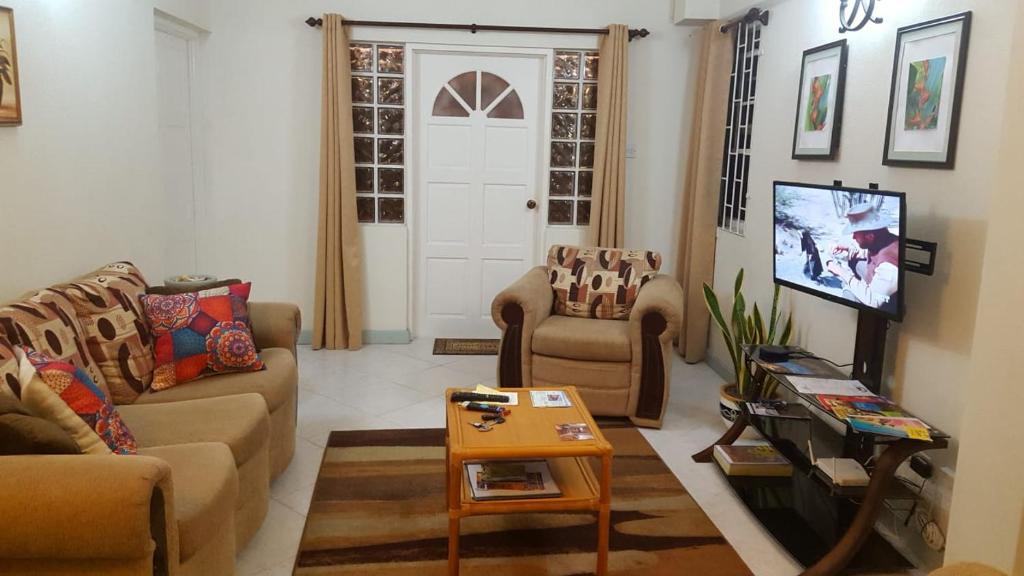 a living room with two couches and a tv at Breezy Apts in Saint Philip