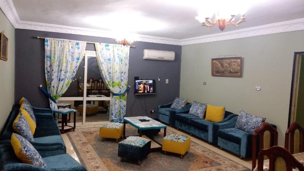 a living room with blue couches and a tv at Makram Ebeid (Families Only) in Cairo
