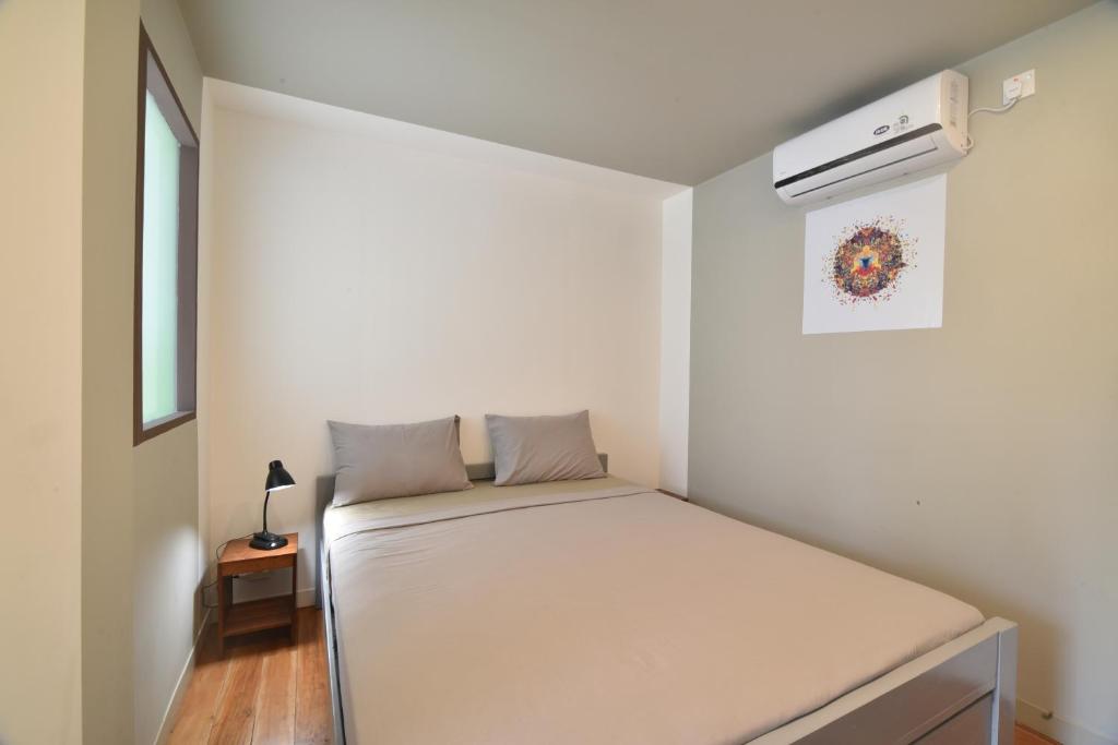 a small bedroom with a bed and a air conditioner at Meno Charm in Gili Meno