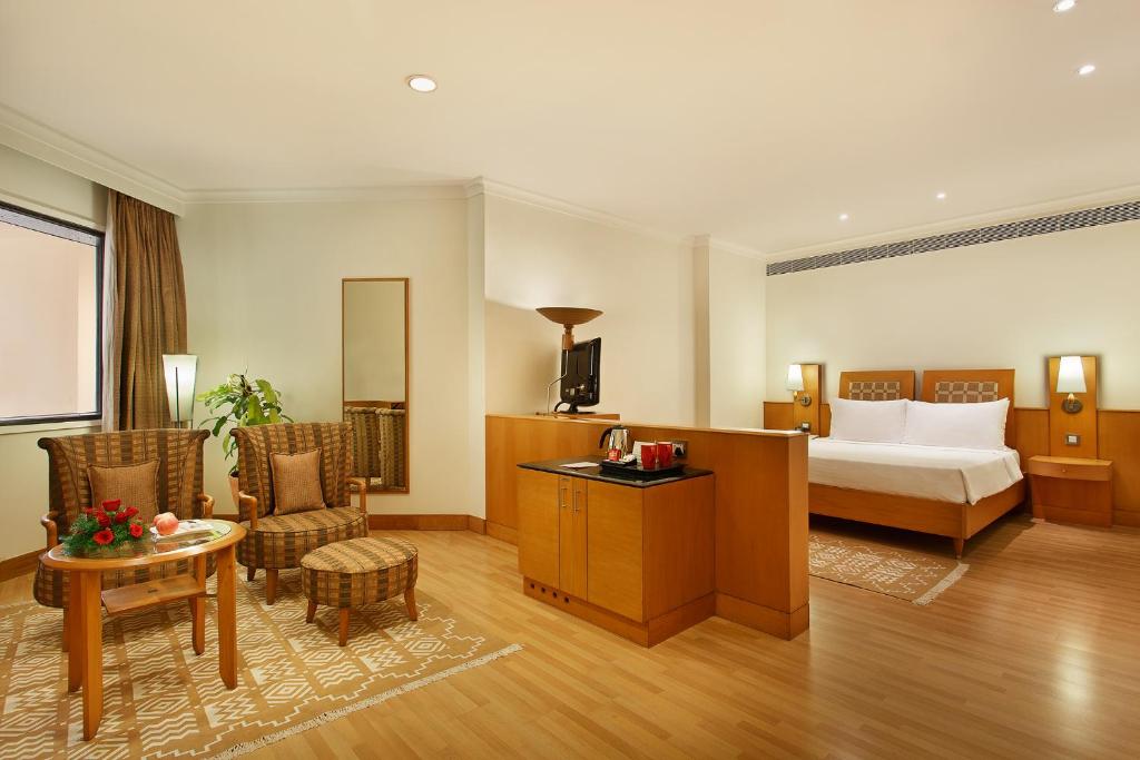a hotel room with a bed and a table and chairs at Trident Chennai in Chennai