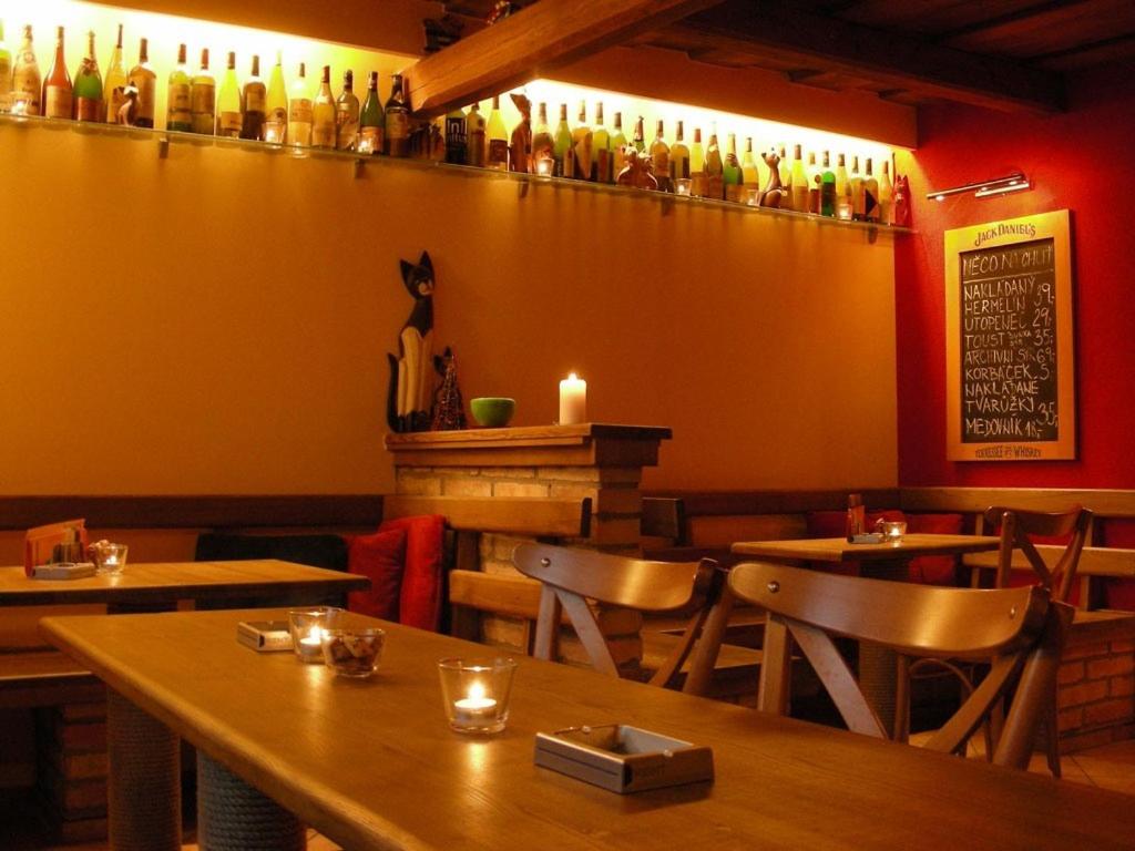 ムテニーチェにあるPenzion U Kočkyのテーブルと椅子、壁にボトルを用意したレストラン