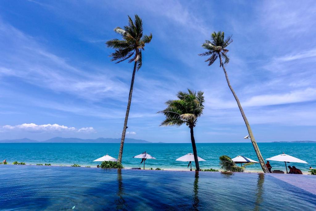 una piscina con palmeras y el océano en Saree Samui, en Mae Nam