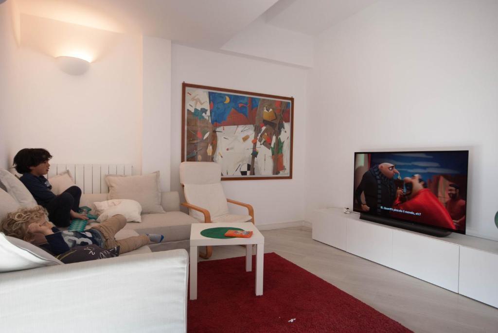 a living room with a tv and a child laying on a couch at Exclusive rooftop apartment with large terrace in Solari/Tortona in Milan