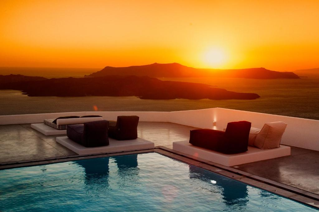 een zwembad met een zonsondergang op de achtergrond bij Amity Suites - Adults Only in Fira