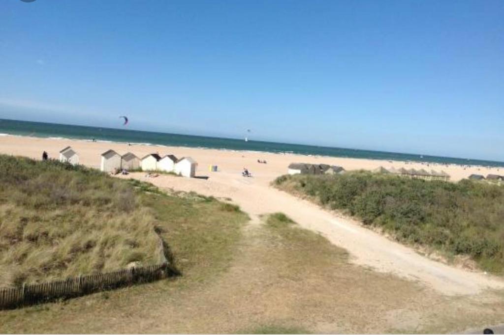 a sandy beach with tents and people on the beach at Le Riva Plage Appartement in Ouistreham