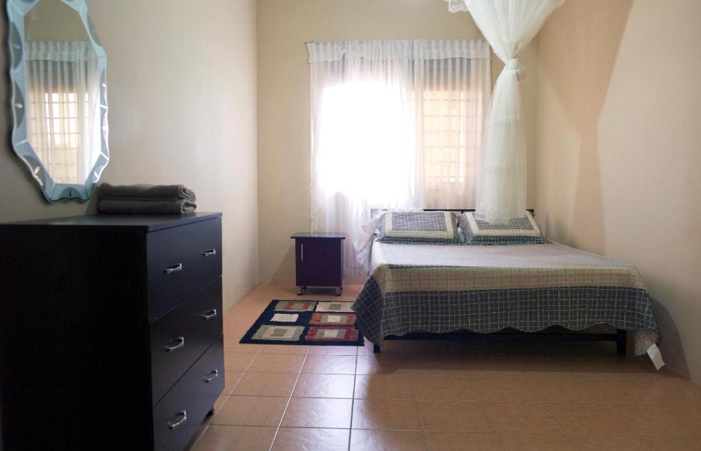 a bedroom with a bed and a dresser and a window at Millie Apartments Ntinda Kampala in Kampala