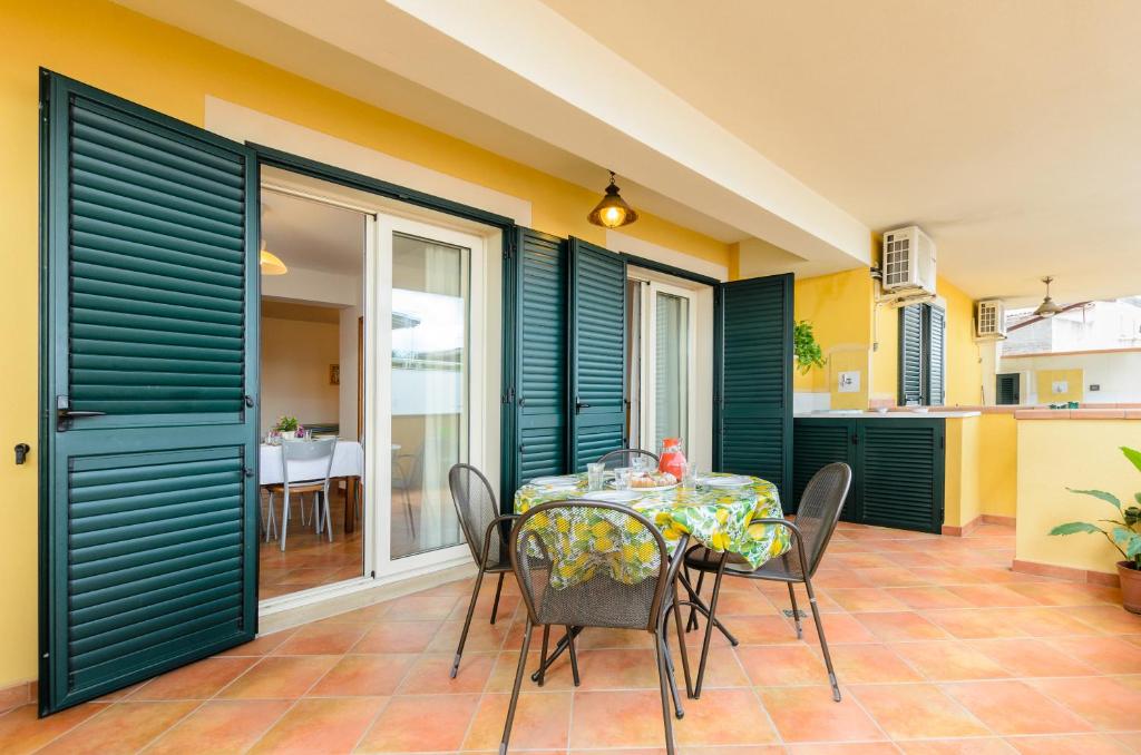 a dining room with green shutters and a table and chairs at Le Tartarughe Aparthotel in Letojanni