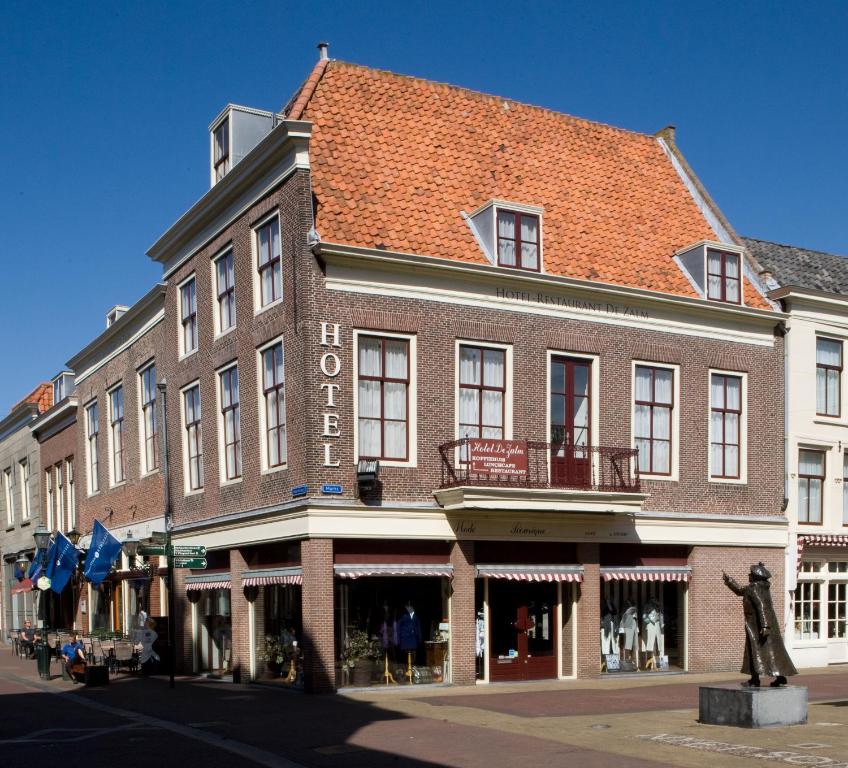a large brick building with a statue in front of it at Fletcher Hotel De Zalm in Brielle