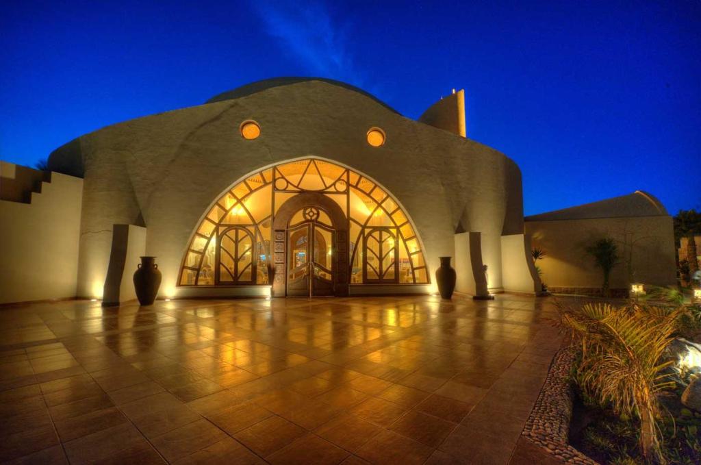 a large building with a large entry way at night at Shams Alam Beach Resort in Abū Ghuşūn