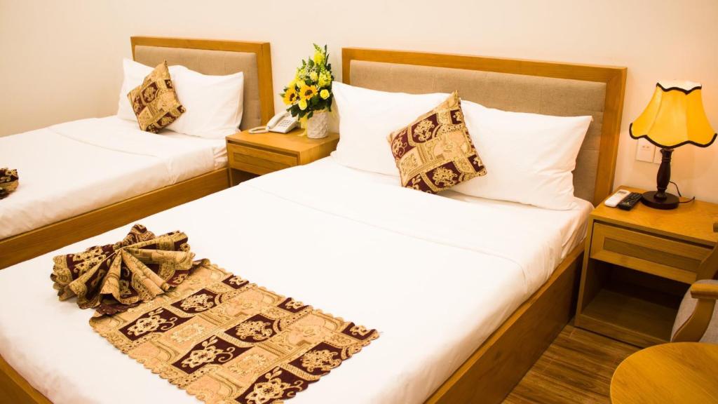 een hotelkamer met 2 bedden en een tafel met bloemen bij Hoài Thương Hotel in Pleiku