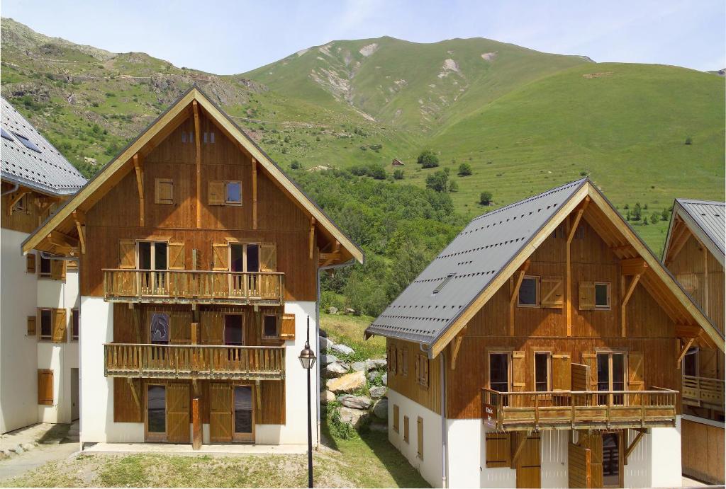 un groupe de maisons avec des montagnes en arrière-plan dans l'établissement Madame Vacances Residence Les Fermes de Saint Sorlin, à Saint-Sorlin-dʼArves